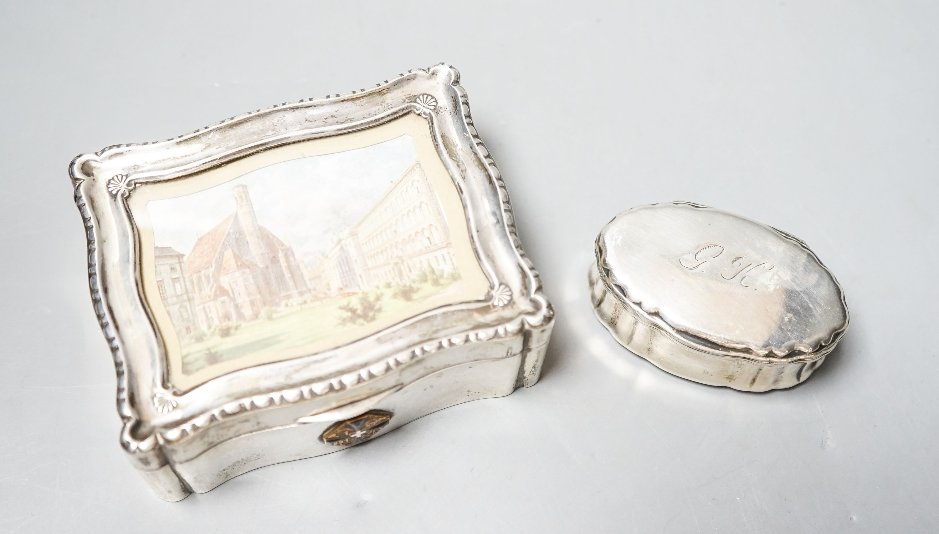 An Austro-Hungarian white metal mounted cigarette box with lid inset with print of a townscape, 12.3cm and a continental white metal oval snuff box.